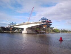 A T-shaped section of bridge being constructed over a river