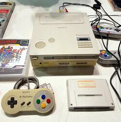 A photo of the only-known SNES-based PlayStation prototype with a controller and disk drive in the foreground.