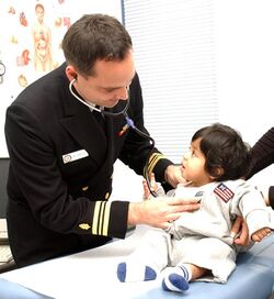 US Navy 031027-N-0000W-001 Family Nurse Practitioner Lt. Cmdr. Michael Service cares for a young girl at the U.S. Naval Hospital (USNH) Yokosuka.jpg