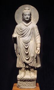 A statue of a standing man wearing a cloak
