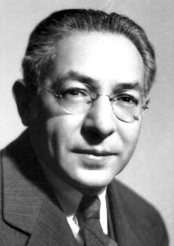 Head and shoulders of man in suit and tie wearing glasses