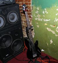 A stage set-up for an electric bass player shows a bass amplifier unit and two bass speaker cabinets.