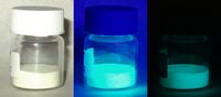 Europium doped strontium silicate-aluminate oxide powder under visible light, long-wave UV light, and in total darkness.