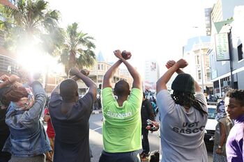 A group of students raise their hands in the air to signal that they have come in peace. Student protest (2015-16) in South Africa against university fee increases.