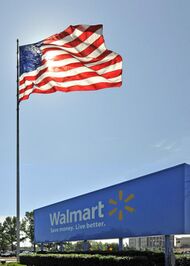 An American flag waving above a Walmart sign at the entrance of an office park