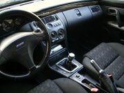 Interior of left-hand-drive car with manual transmission, handbrake, analogue dials, and rotary fan and temperature controls