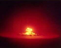 Fireball of Upshot-Knothole Annie nuclear test with several vertical smoke trails from rockets used to gauge shock front progress
