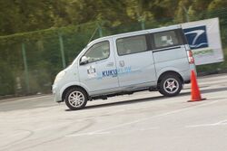 Small passenger van with alloy wheels driven at speed around a traffic cone
