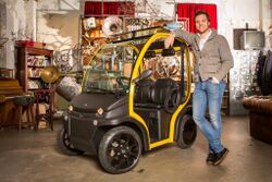 Matteo Maestri, CEO of Estrima, standing beside a Birò microcar in what seems to be an apartment