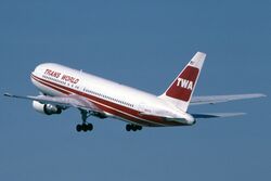 TWA jetliner in red and white livery during takeoff, with landing gears still down.