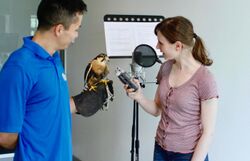 Actress recording podcast in microphone with Earth Rangers handler holding a bird to record vocals