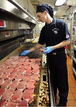 US Navy 100821-N-2686K-030 Culinary Specialist Seaman Cody D. Cunningham prepares pork chops for lunch in the galley aboard USS George H.W. Bush (CVN 77).jpg