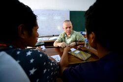 U.S. Navy Capt. Rod Moore, center, 30th Naval Construction Regiment commander, helps two Timorese college students complete an English exercise in Dili, East Timor, Oct. 29, 2013 131029-N-VN372-319.jpg