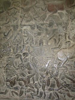 A black stone relief depicting several men wearing a crown and a dhoti, fighting with spears, swords, and bows. A chariot with half the horse out of the frame is seen in the middle.