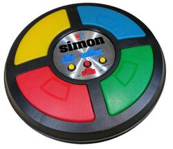 The game is a circular disc divided into four quarter circle buttons each with a different color. In the center are the game mode controls
