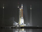 A 365-foot-tall orange and white rocket lifting off of Pad 39B at the Kennedy Space Center, at night