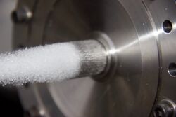 A pintle injector is shown during a cold flow test. The outer flow path is active.
