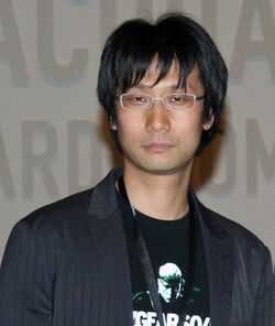 An asian man stands stoically looking at the camera.
