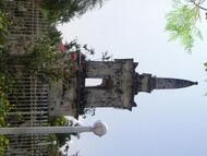 Tall stone memorial with spire and surrounded by a metal fence.