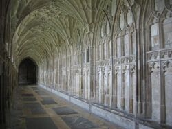 View along a stone cloister passage showing the conically shaped sections of the vault, and the carved stone panelling of the walls.