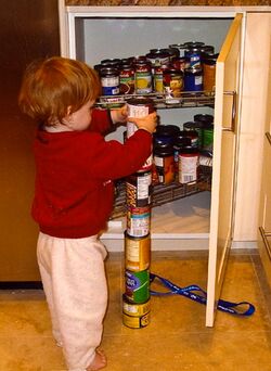 An autistic toddler plays by stacking cans