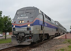 A gray diesel locomotive with a blue stripe and several thinner white stripes. The stripes run along the sides and wrap across the front, where they pinch slightly