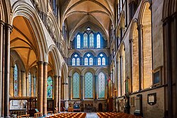 A view into the south transept at Salisbury shows a harmonious arrangement of lancet arches rising in three tiers of various sizing and grouping. The details are enhanced by narrow attached shafts of dark-coloured Purbeck marble. The ribbed vault is of a simple form.