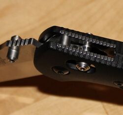 Close-up of the pivot joint of a folding knife, showing locking barrel inserted through holes in the handle