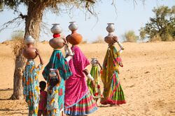 Women and children carrying pots filled with water in Thar desert