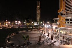 Plaza at night with seats and bell tower in background