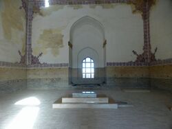 Photograph of the interior of a mausoleum showing a window and decorated tile on the walls