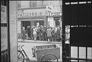 People queuing in the street outside a bakery
