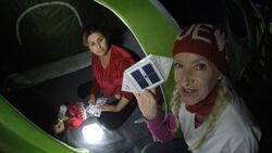 Full-time volunteer, Dr. Alison Thompson is handing a Syrian family a solar lantern called SolarPuff to light their dark tent at the Idomeni refugee camp in Greece. 2015