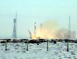 Picture of a rocket launch. The ground near the launch pad is covered in snow.