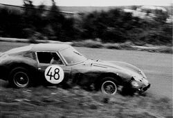 Black and white photo of a sports car number 48 driving left to right, foreground speed-blurred