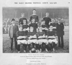 A black-and-white photograph of a football team lining up before a match. Four players, wearing dark shirts, light shorts and dark socks, are seated. Four more players are standing immediately behind them, and three more are standing on a higher level on the back row. Two men in suits are standing on either side of the players.