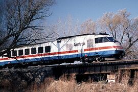 A white passenger trainset with red, white, and blue stripes of equal width on the side under the windows