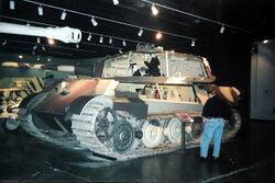 A side view of a large turreted tank in a museum, with sections of its superstructure and turret cut away.