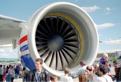 Crowd of people standing around a large engine of a Boeing 777