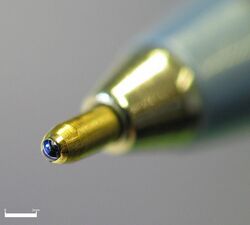 Close-up picture of the tip of a ballpoint pen showing the ink-covered ball.
