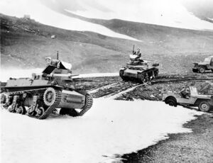 Two Marmon-Herrington tanks, with one in the fore ground and one in the background. There are also two jeeps in the background.