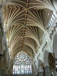 The interior of the nave at Exeter shows a great richness and diversity of decoration. Above the Gothic arcade runs an ornately sculptured blind gallery, above which rise clerestory windows full of Geometri tracery. The wide western window of nine lights beneath an upper rose fills the western end. The vault has many ribs of strong profile, which spring out in clusters like palm branches.
