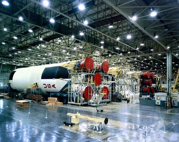 A large horizontal rocket with USA painted on the side inside of a manufacturing facility
