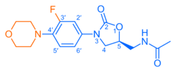 Skeletal formula of N-{[(5S)-3-[3-fluoro-4-(morpholin-4-yl)phenyl]-2-oxo-1,3-oxazolidin-5-yl]methyl}acetamide, highlighting the morpholino and fluoro groups in orange, with the rest in blue. The carbon atoms of the parent chain are numbered.