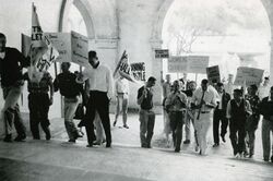 Men marching up the Frary Dining Hall steps carrying handwritten protest signs