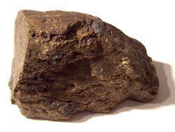 A brown block of irregular shape and surface, about 6 cm in size.