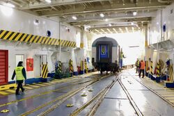 Image showing a railcar on rails inside the white interior of a ferry.