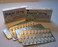 Two packages of Atarax, a brand name for hydroxyzine, in Suomi. Four foil packages of pills sit in front of two boxes, one labeled as having 25 pills and the other labeled for 100.