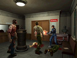 A young police officer is defending himself against a group of attacking zombies with a shotgun. The scene takes place in a small room decorated with pieces of art.