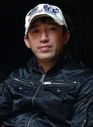 A photograph of a Japanese man wearing a baseball cap.